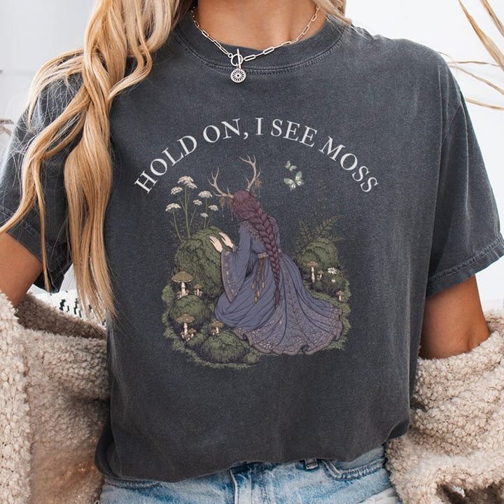 "Hold on, I see moss" text features a doe-antlered woman kneeling in a mossy forest.