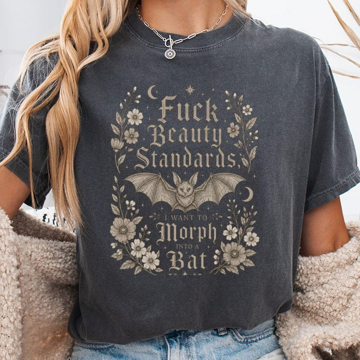 Dark t-shirt with "Fuck Beauty Standards I Want to Morph Into a Bat" graphic.