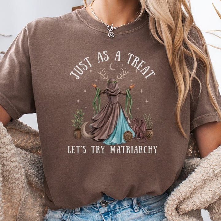 Brown t-shirt with "JUST AS A TREAT LET'S TRY MATRIARCHY" text and whimsical illustration.