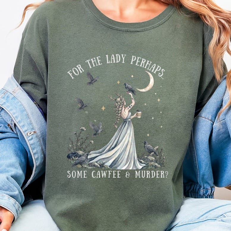 An olive green crewneck sweatshirt featuring a graphic of a woman surrounded by ravens and the text "FOR THE LADY PERHAPS... SOME CAWFEE & MURDER?".