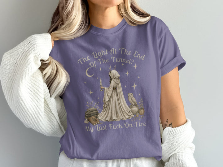 A woman wearing a purple t-shirt with a hooded figure, an owl, books, and text.