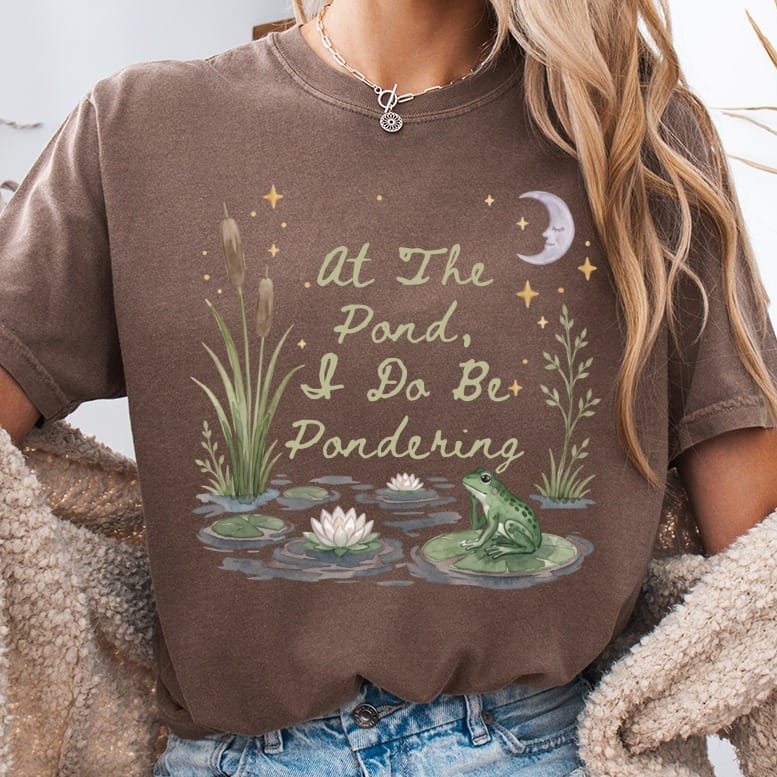 Brown t-shirt with a pond scene, frog, and text "At The Pond, I Do Be Pondering."