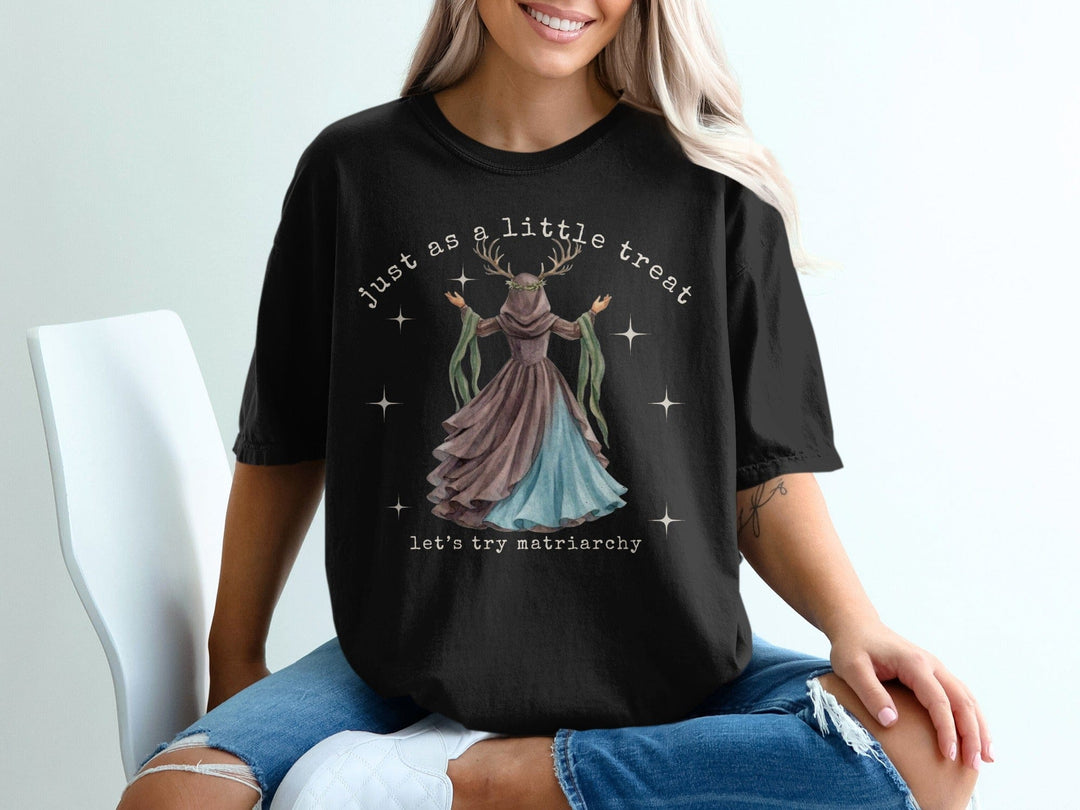 Black t-shirt with "Just as a little treat, let's try matriarchy" text and mystical deer woman graphic.