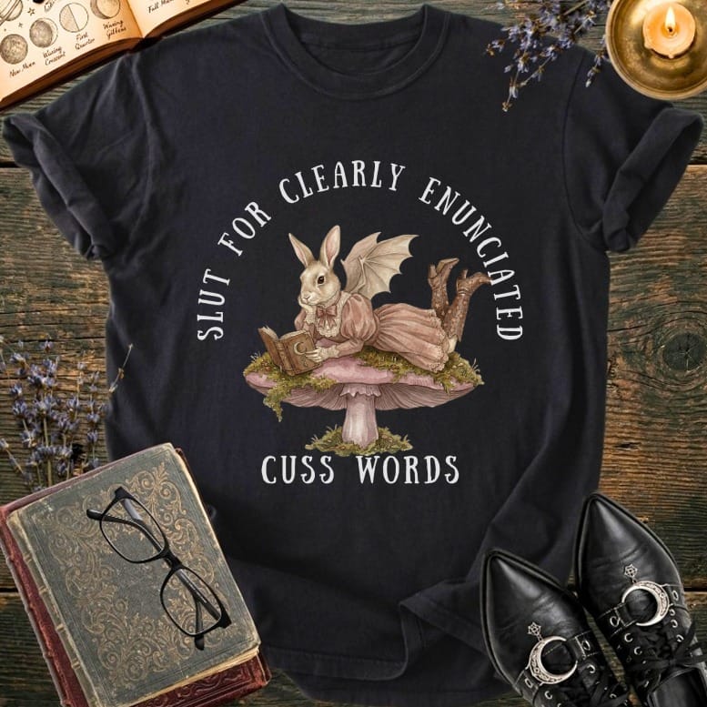 T-shirt with a rabbit in a dress reading on a mushroom, text "SLUT FOR CLEARLY ENUNCIATED CUSS WORDS".