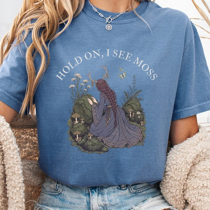 "Hold on, I see moss" text above woman with antlers and elaborate dress in forest scene.