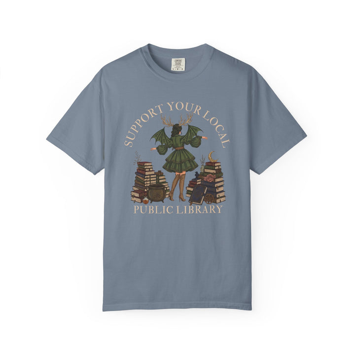 Graphic tee with witch reading among books, "Support Your Local Public Library" text.
