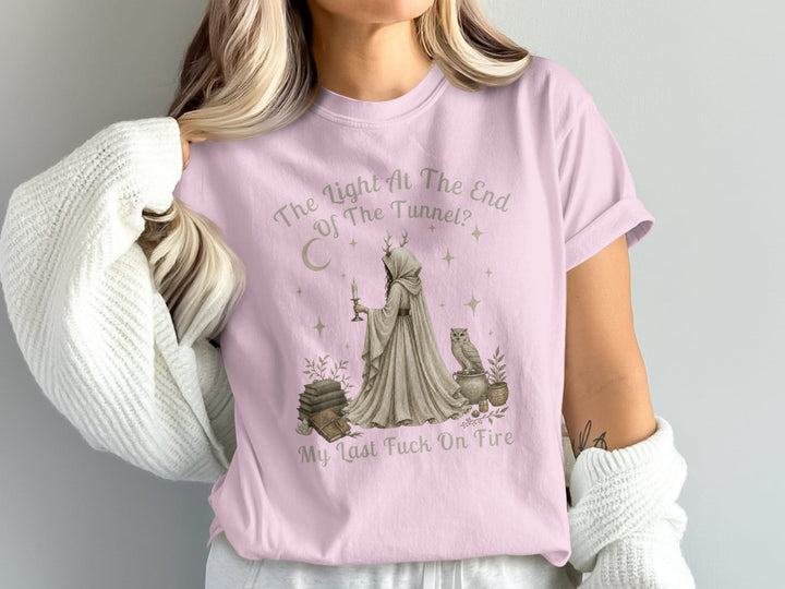 Pink t-shirt with graphic art of a robed figure holding a candle, owl, books, and text.
