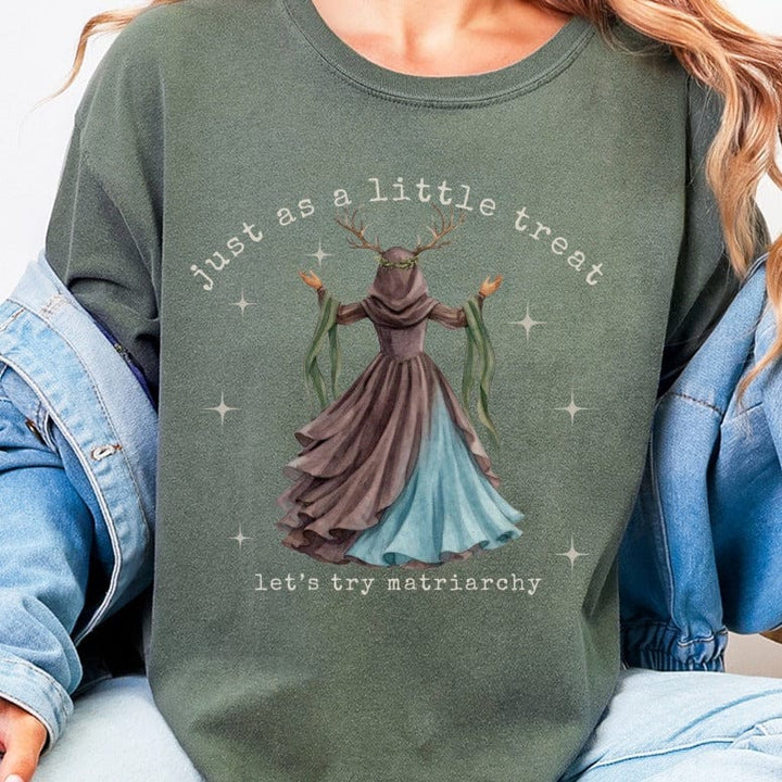 Green t-shirt with "just as a little treat let's try matriarchy" and illustration of a woman.