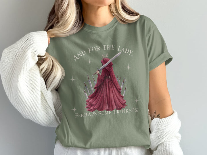 Woman wearing green t-shirt with "And for the lady? Perhaps some trinkets?" and sword imagery.