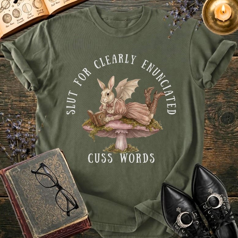 Bunny in dress reads book on mushroom, text says "SLUT FOR CLEARLY ENUNCIATED CUSS WORDS".