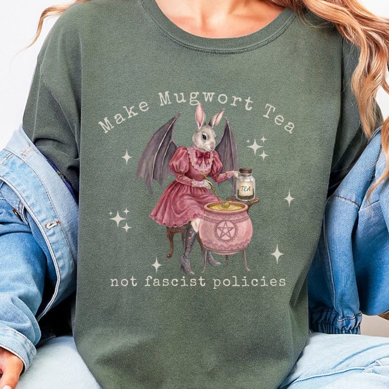 Bunny in dress brewing tea in cauldron, "Make Mugwort Tea not Fascist Policies."