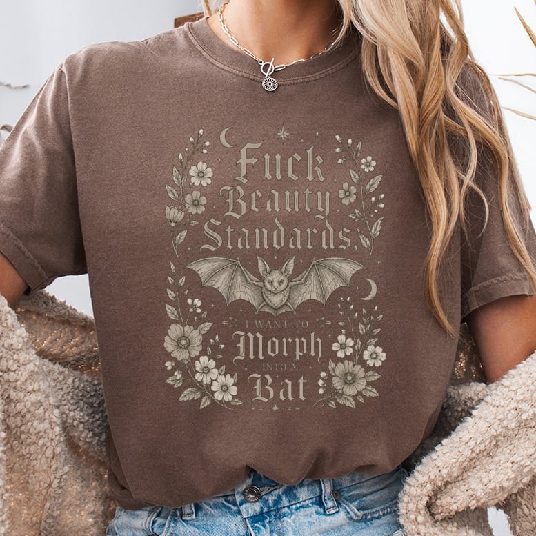 Brown t-shirt with bat, moon, and flowers graphic reading "Fuck Beauty Standards I Want to Morph into a Bat".