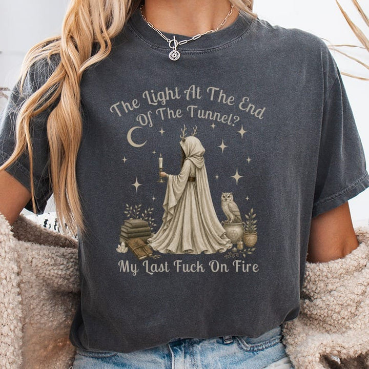 Dark t-shirt with a hooded figure holding a candle, owl, books, and text.