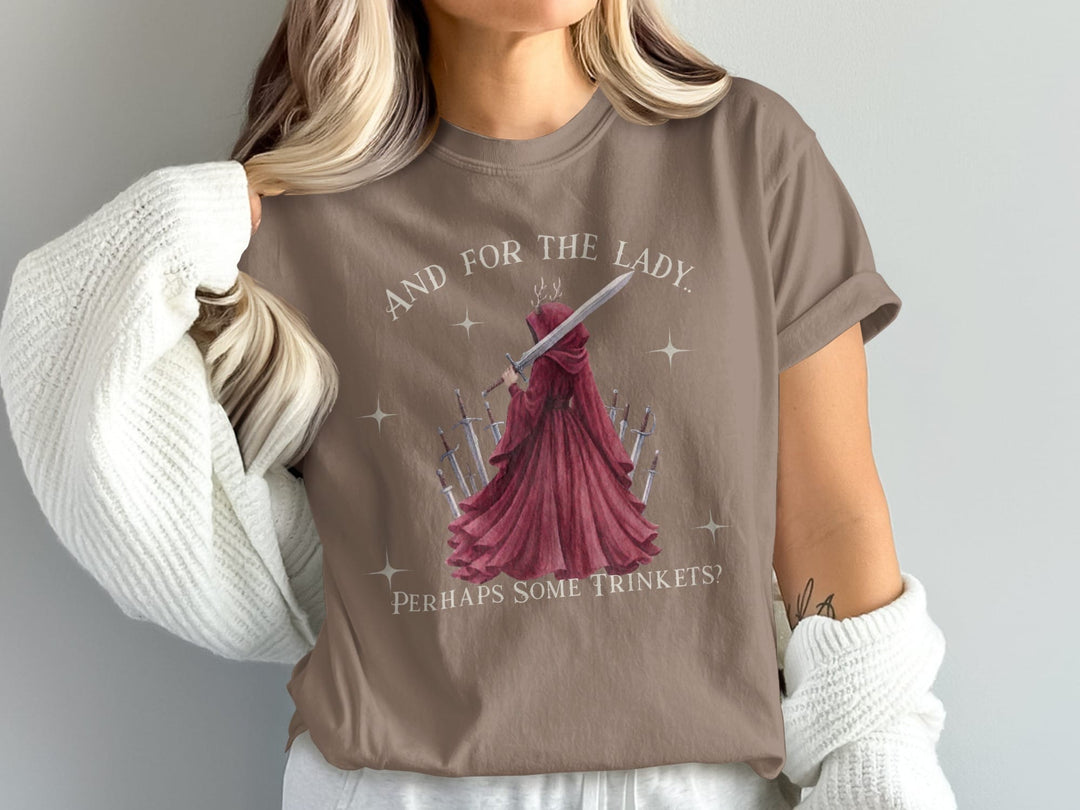 Brown t-shirt with "And for the lady. Perhaps some trinkets?" and a figure in red with swords.