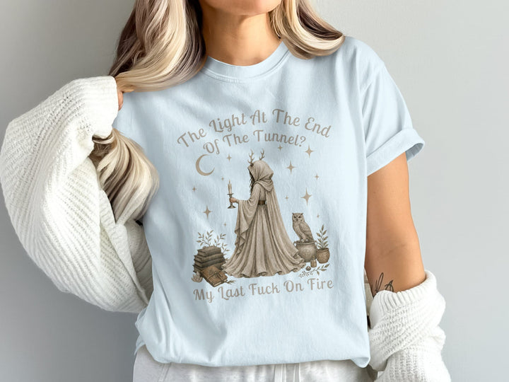 Light blue t-shirt with a graphic featuring a hooded figure holding a candle, an owl, and text.