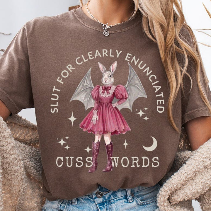Brown t-shirt with a graphic of a rabbit in a pink dress and bat wings.