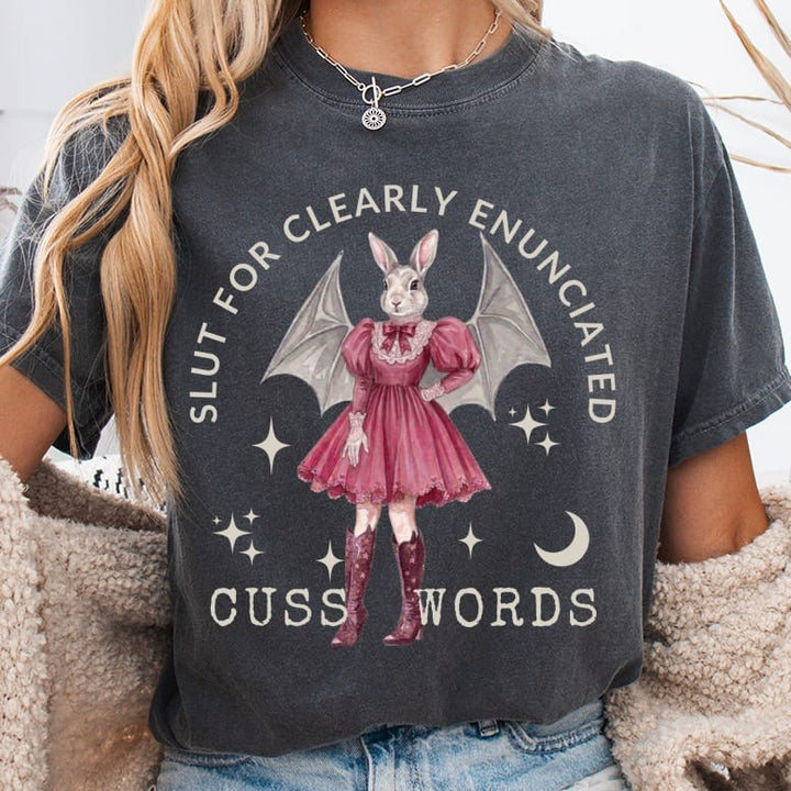 T-shirt with a bunny in a pink dress and bat wings, text "SLUT FOR CLEARLY ENUNCIATED CUSS WORDS".