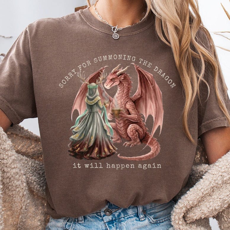 Woman wearing a brown t-shirt with a dragon and text, "sorry for summoning the dragon it will happen again."