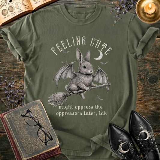 Olive green t-shirt with winged bunny on broom and text.