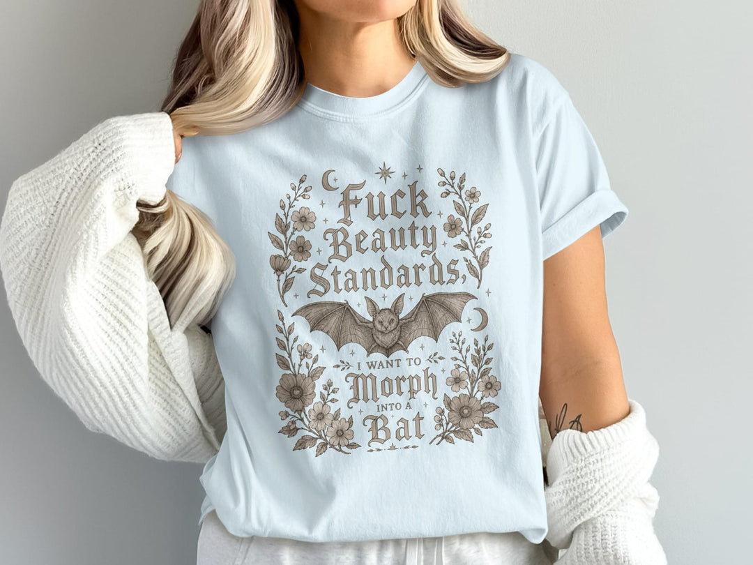 Light blue t-shirt with floral border, bat, and text: "Fuck Beauty Standards, I Want to Morph Into a Bat".